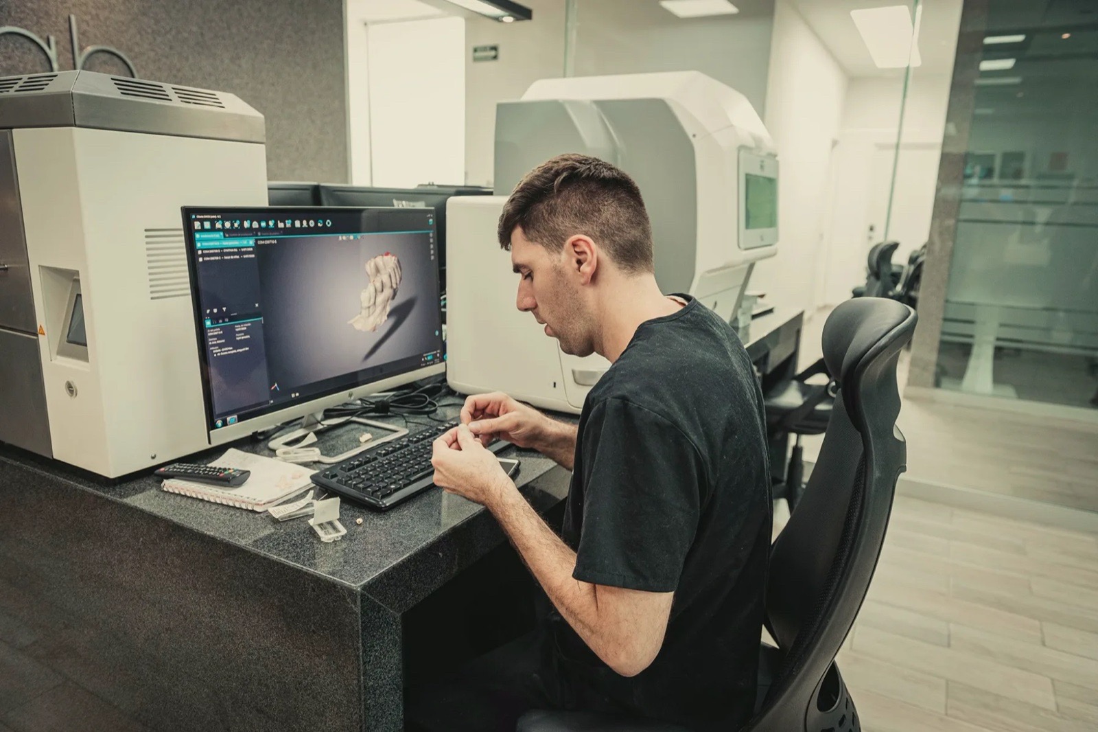Técnico dental diseña una pieza en tercera dimensión en una estación CAD del laboratorio de la familia Dent