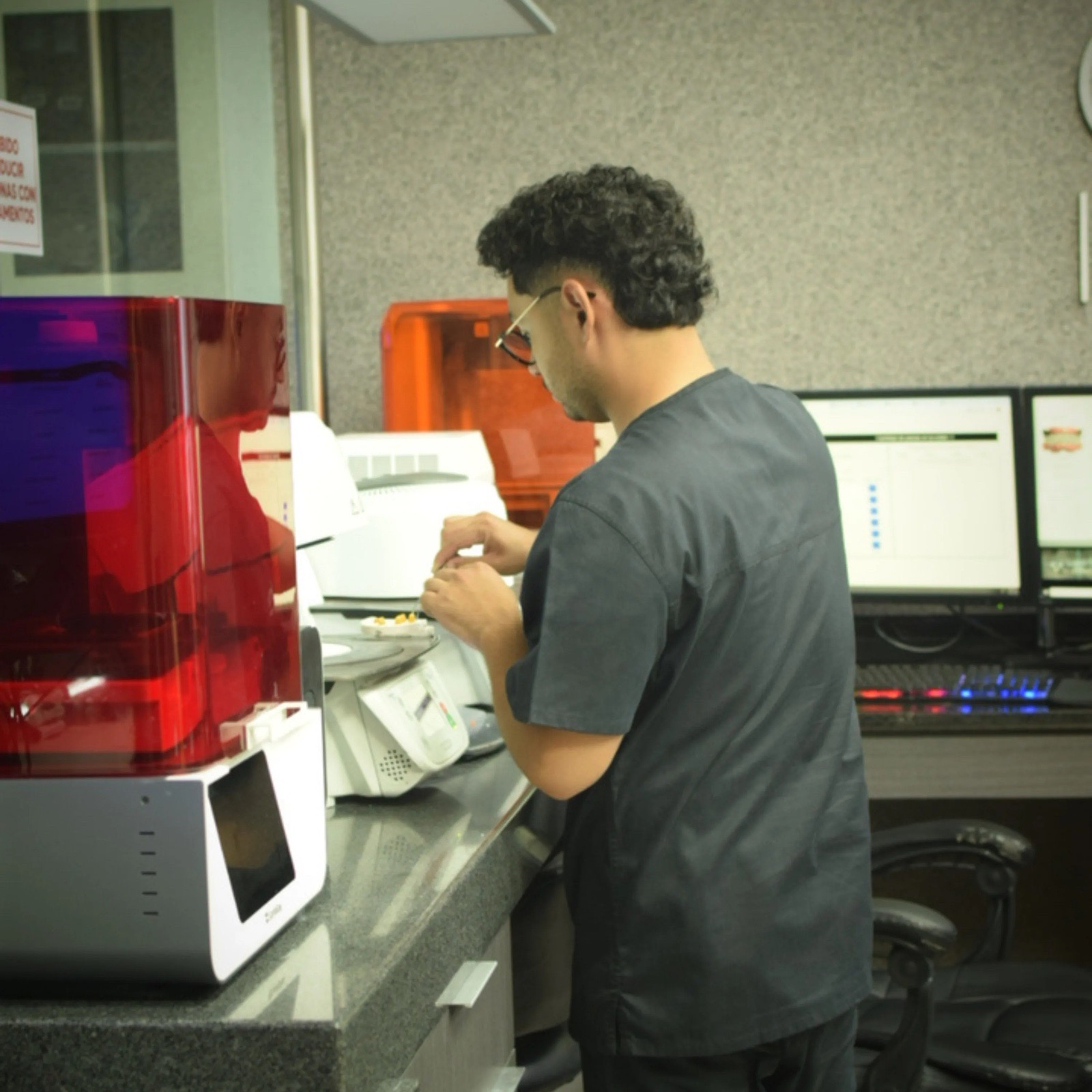 Técnico de Dent Lab trabaja un modelo dental junto a las impresoras 3D de resina del laboratorio
